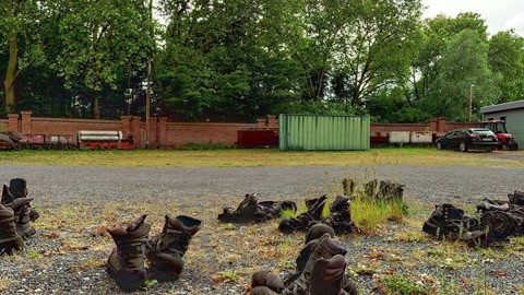 Rows of worn boots in courtyard — Stillmotion