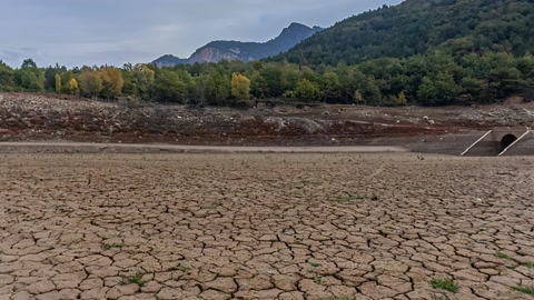Cracked lakebed beneath cloudy mountains — Stillmotion