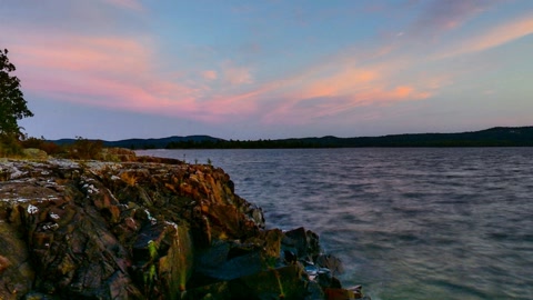 Rocky forest shoreline at sunset — Stillmotion