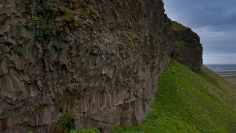 Cliffside waterfall under cloudy skies — Stillmotion
