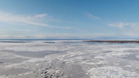 Frozen snowfield beside winding water — Stillmotion