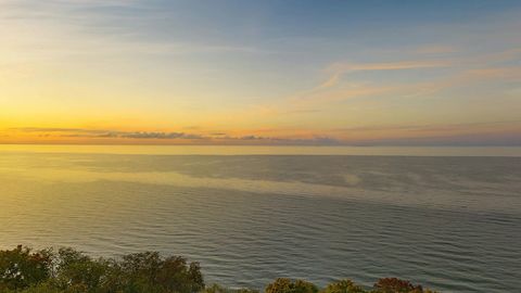 Sunset over forested lakeshore cliffs — Stillmotion